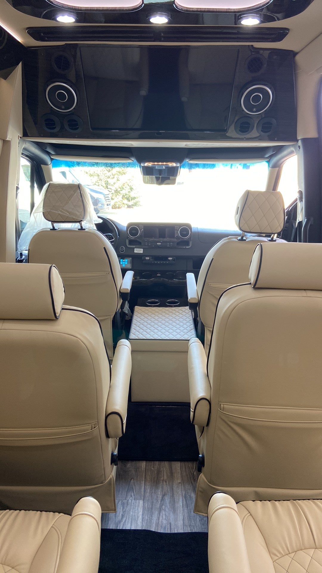 parked by a modern building on a sunny day.|This sleek black Mercedes Sprinter