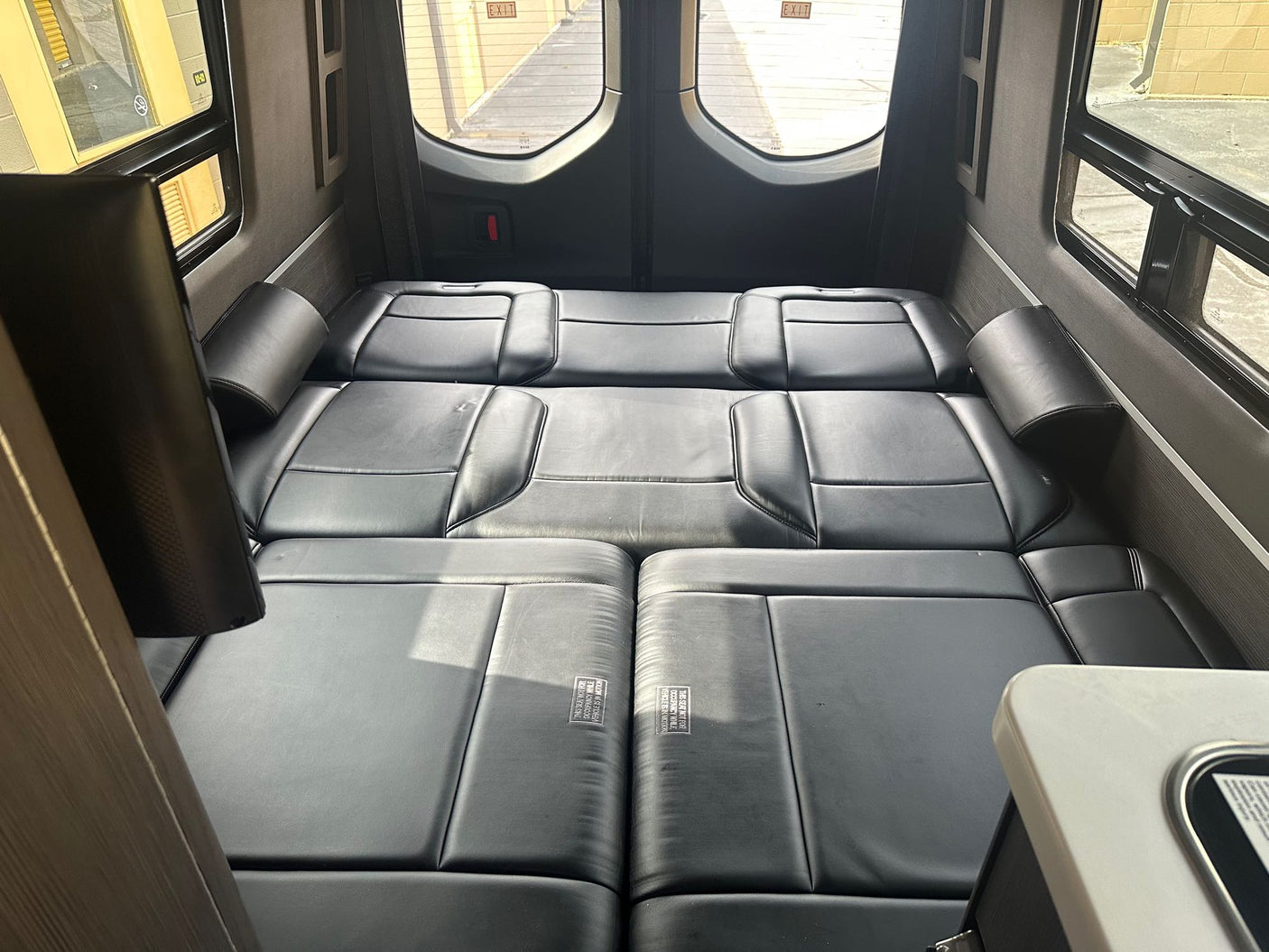 entertainment screen & ceiling vent.|This RV rental features a compact camper van kitchen with a stove
