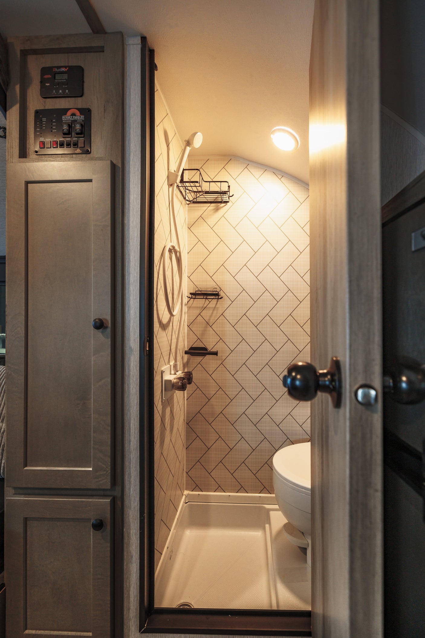 Inside an RV rental: a modern, space-saving bathroom featuring a shower, toilet, and system controls.