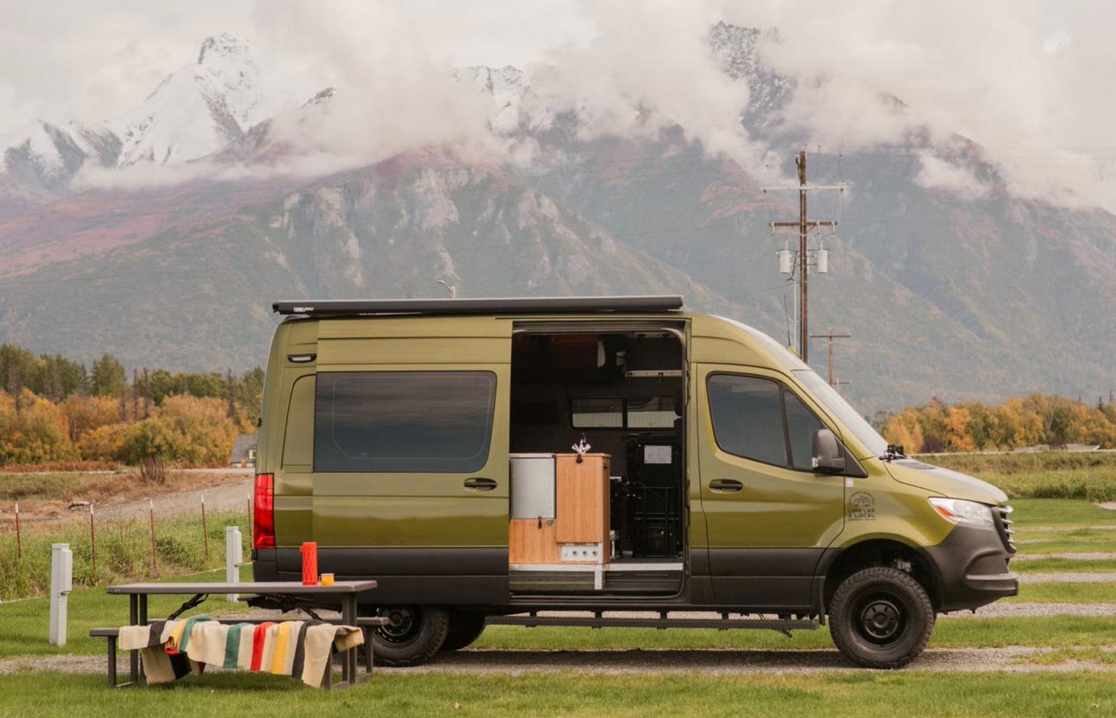 Scenic rv rental: A green camper van with open door & picnic table