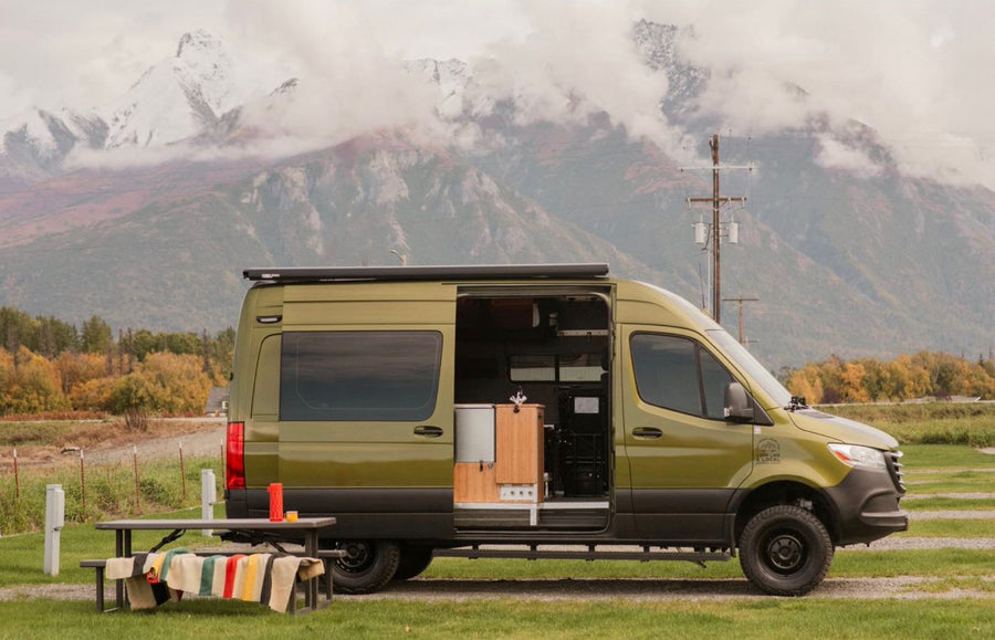 Scenic rv rental: A green camper van with open door & picnic table