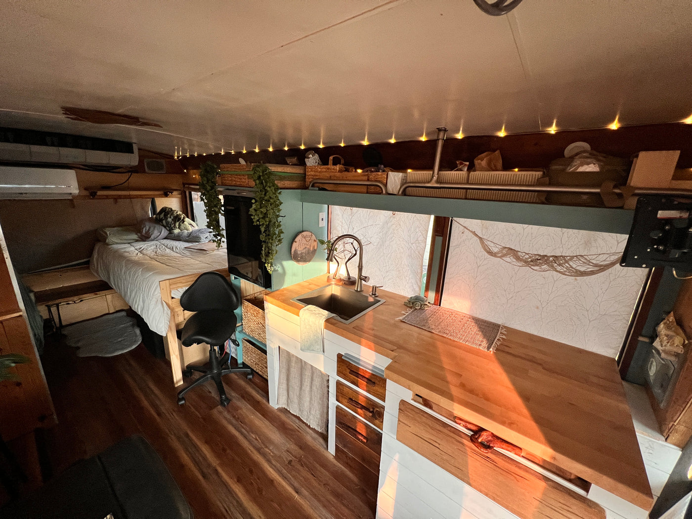Experience cozy living in this RV rental's interior, featuring a bed, kitchen with sink, and wood accents. — photo 15