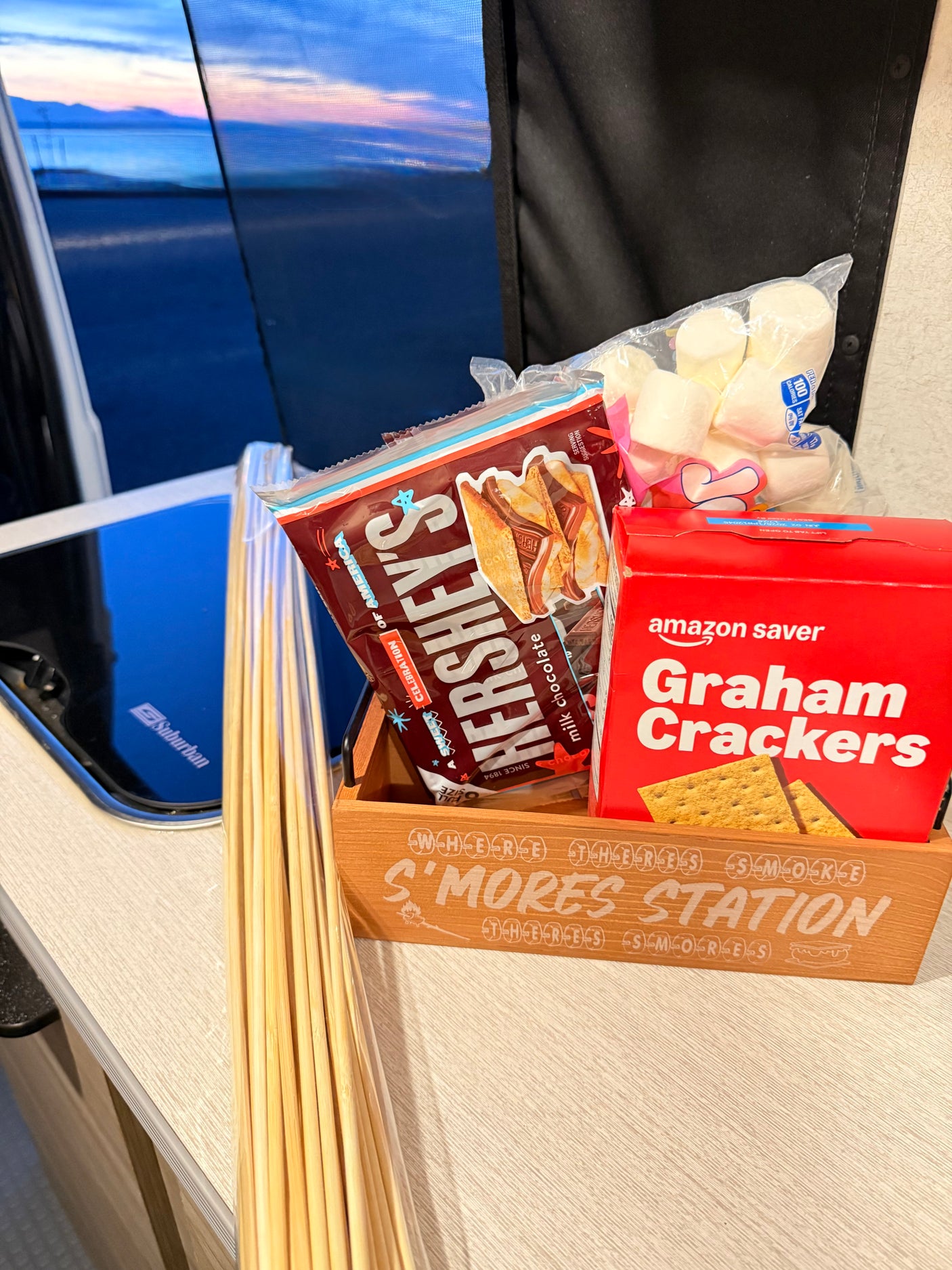 S'mores station with Hershey's, graham crackers, marshmallows, and roasting sticks, perfect for an rv rental with a sunset view.