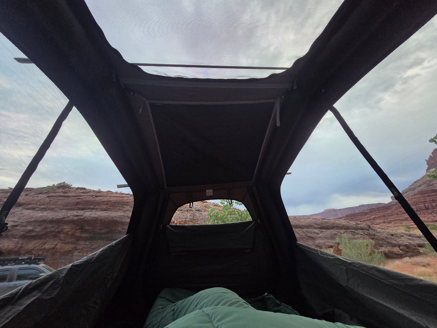 Relaxing inside a rooftop tent, looking out at a stunning red rock desert landscape. Ideal for an RV rental camping trip.