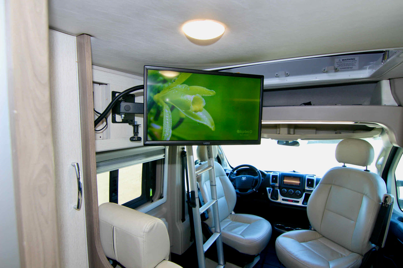 Inside an RV rental: a modern interior with a mounted TV, comfortable front seats, and a clear view of the cockpit.