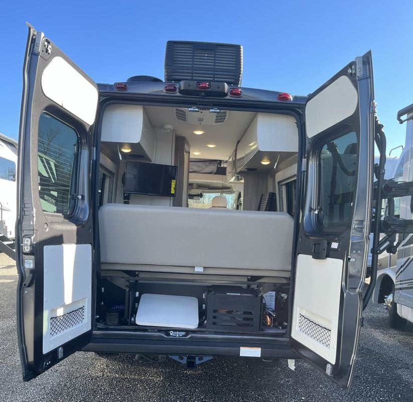 Explore this RV rental: a camper van with rear doors open, revealing a comfy bed, mounted TV, and smart storage for your adventures.