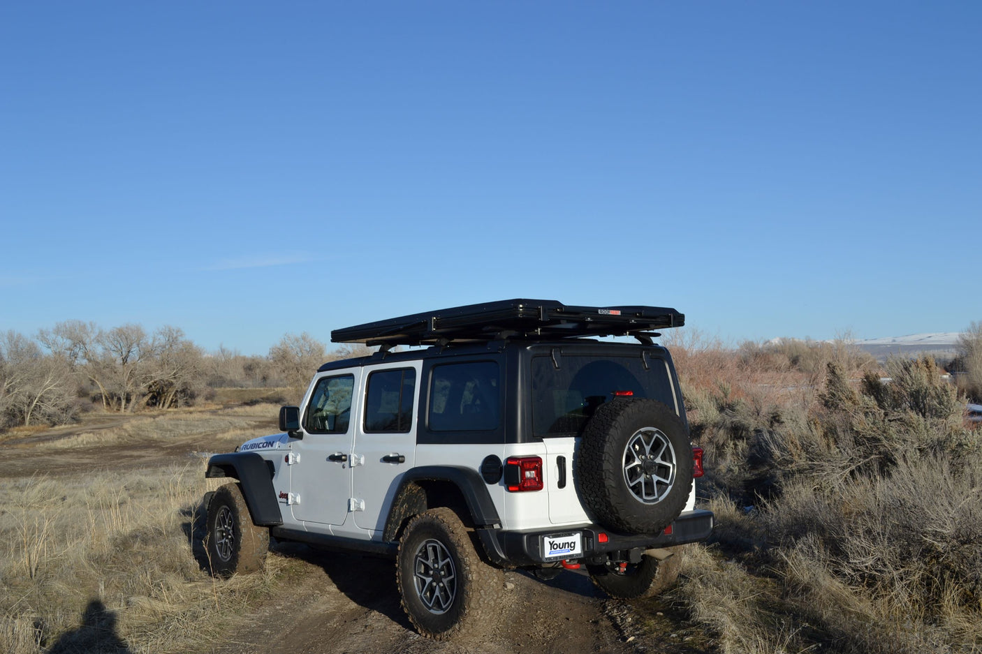 Explore trails with this white Jeep Wrangler Rubicon, featuring a rooftop tent. Great rv rental for off-road adventures.