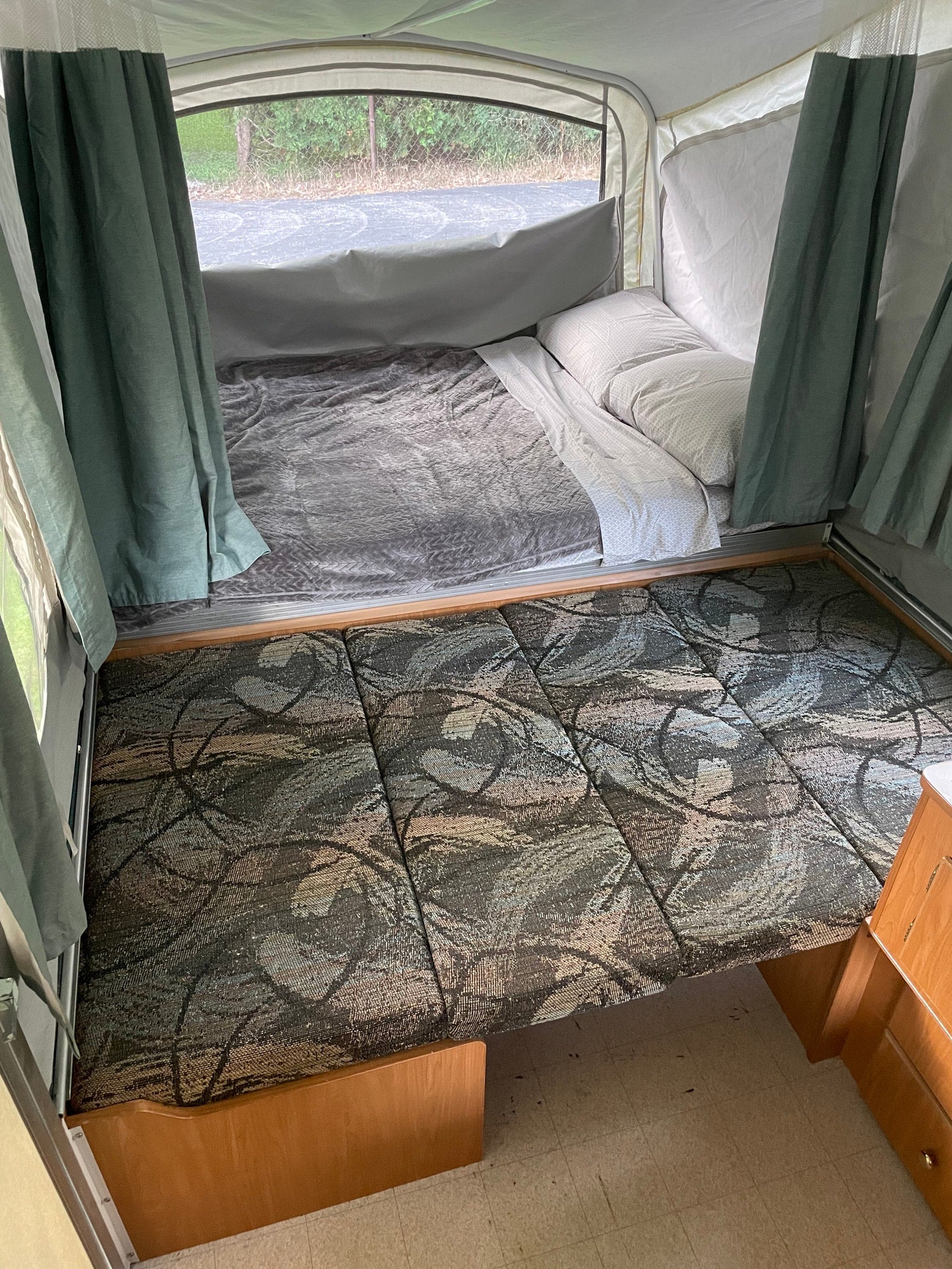and a window view of greenery.|Pop-up camper interior with dining area