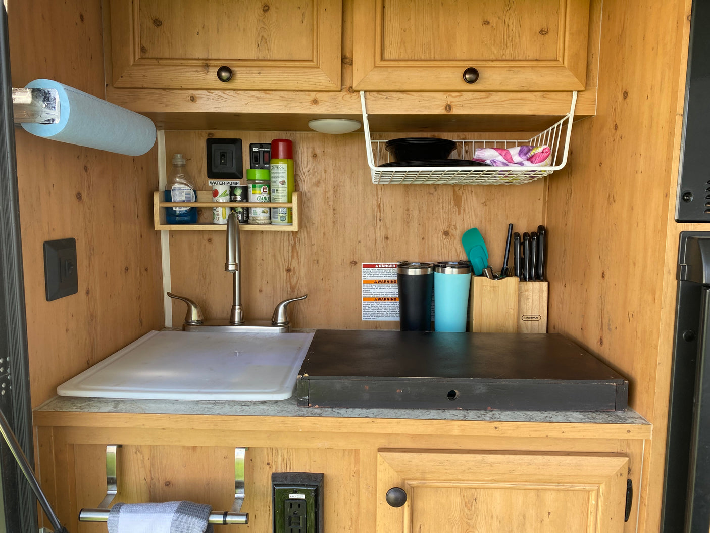 RV rental kitchenette: sink, paper towels, spices, dishes, and knife set ready for your travels.