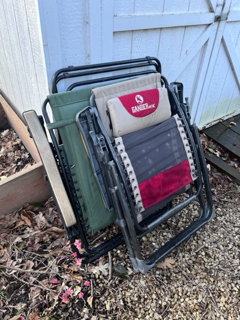 Stacked GANDER OUTDOOR chairs near a shed. Perfect comfort for your RV rental or camping trip.
