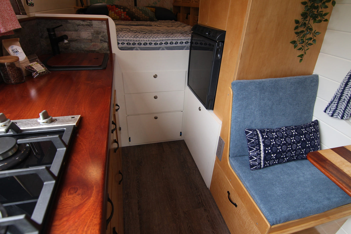 RV rental interior with a compact kitchen, comfortable bed, refrigerator, and cozy seating area with storage drawers.