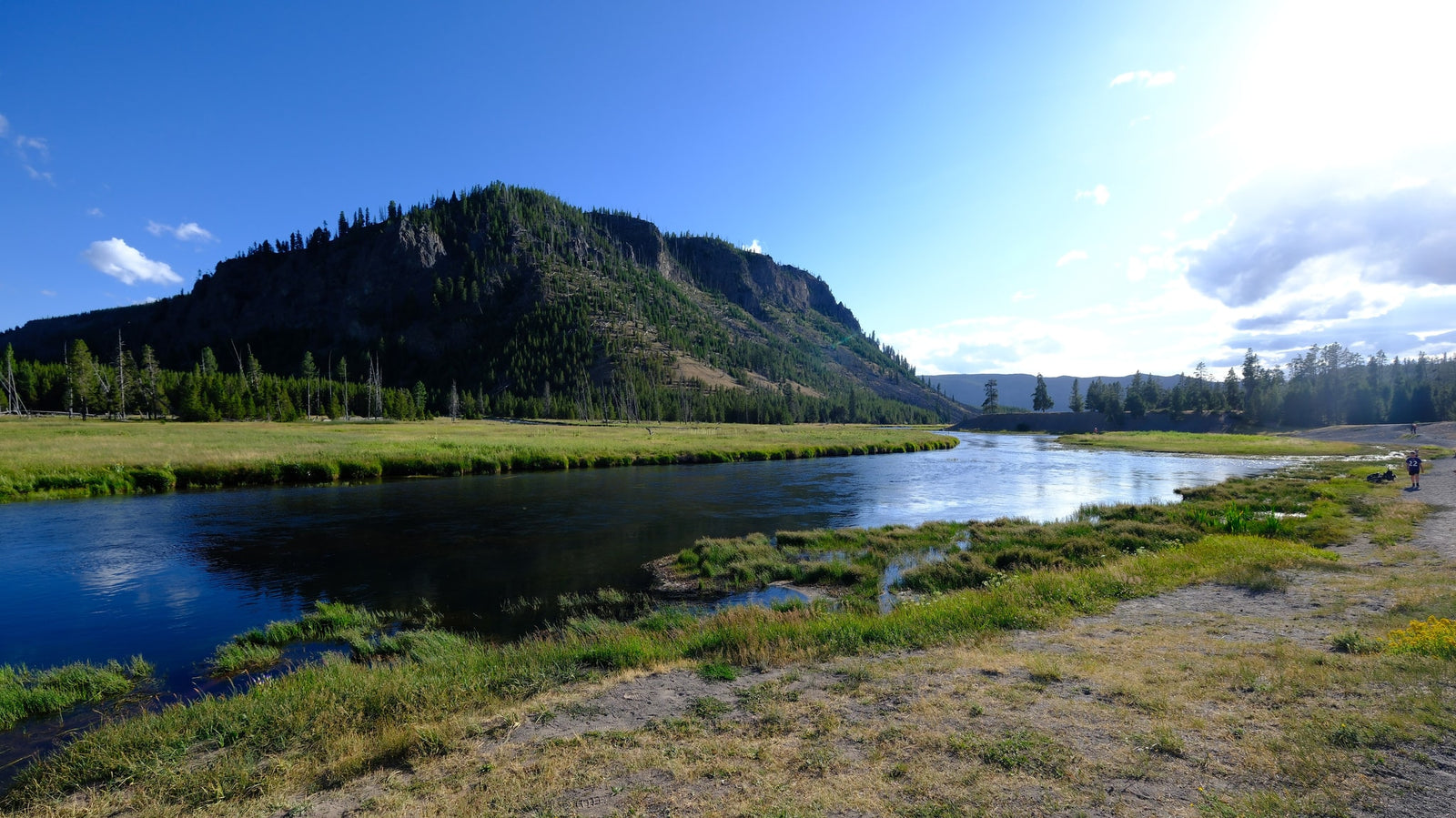 and river behind it.|RV rental travelers explore Yellowstone's Mammoth Hot Springs boardwalk