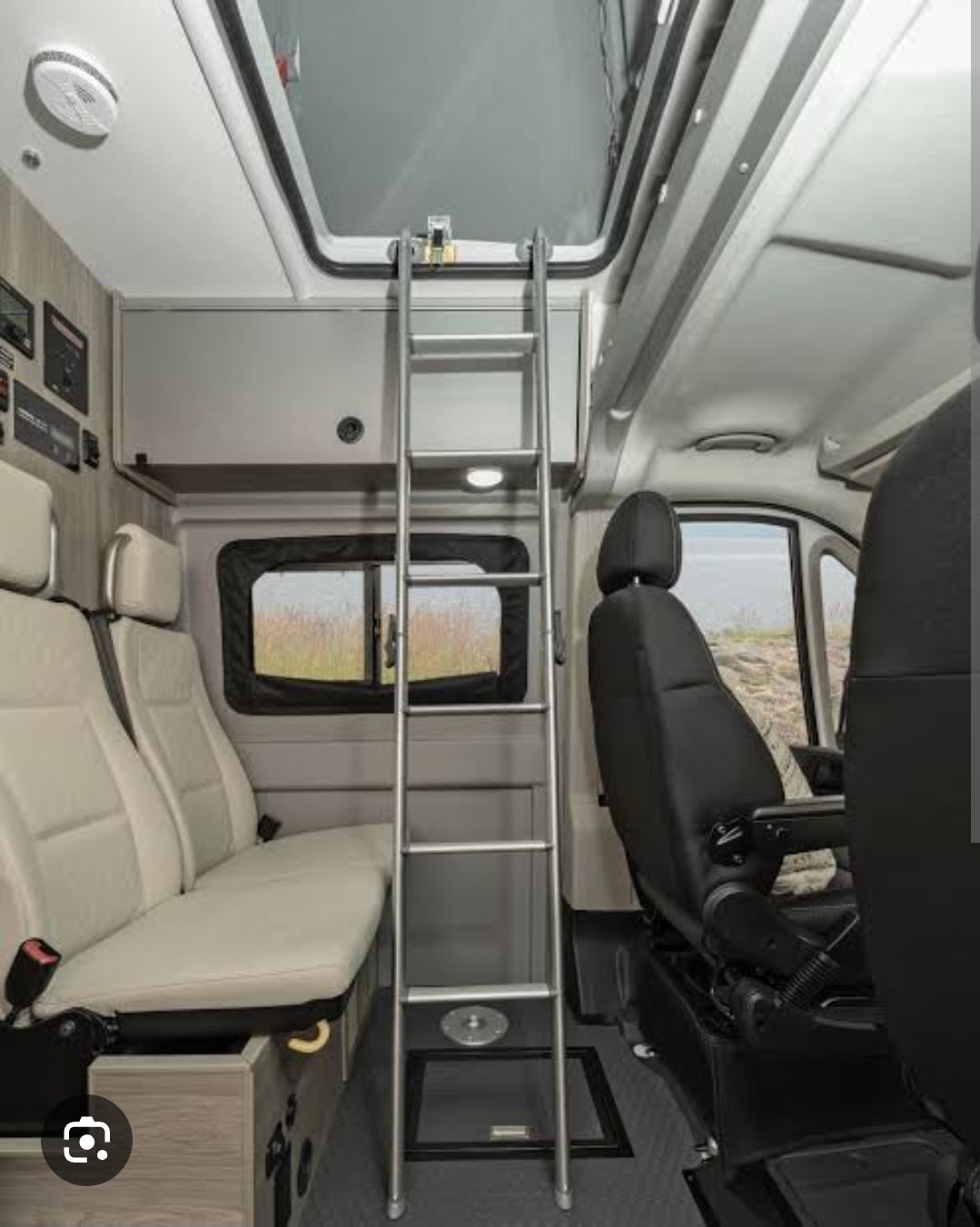 RV rental interior: A camper van with a ladder leading to an upper bunk, comfortable seating, and a ceiling skylight.