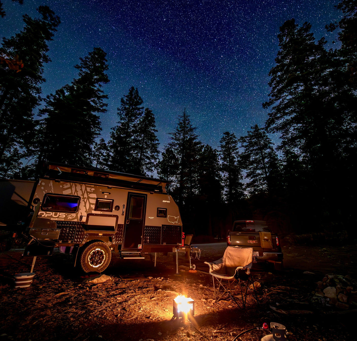 Stargazing awaits! An Opus off-road camper (RV rental) illuminates a forest campsite under a dazzling starry sky with a campfire.|Cozy rv rental campsite at dusk. Opus OP15 pop-up camper featuring an illuminated awning