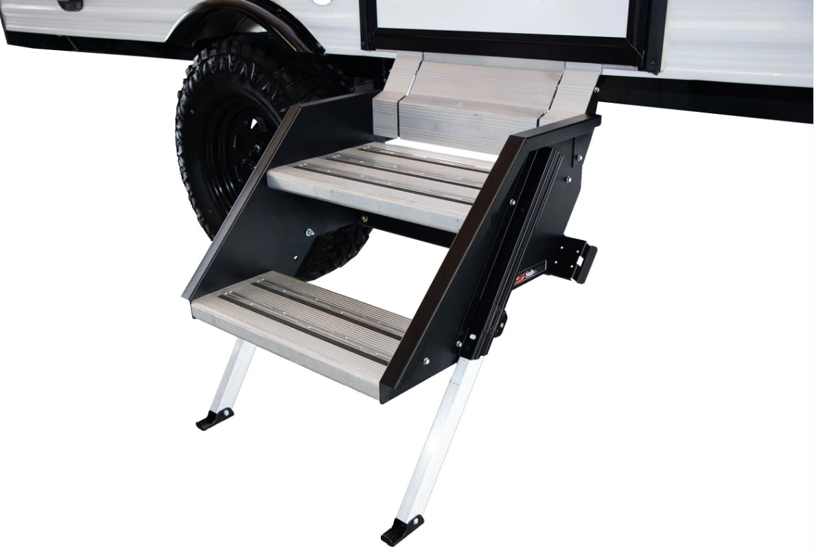 Sturdy, multi-level aluminum RV rental entry steps extended from a white camper with a rugged tire.