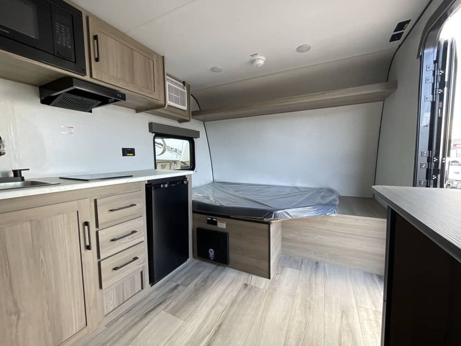 and awning under a sunny sky.|Cozy rv rental interior showing a compact kitchen with microwave