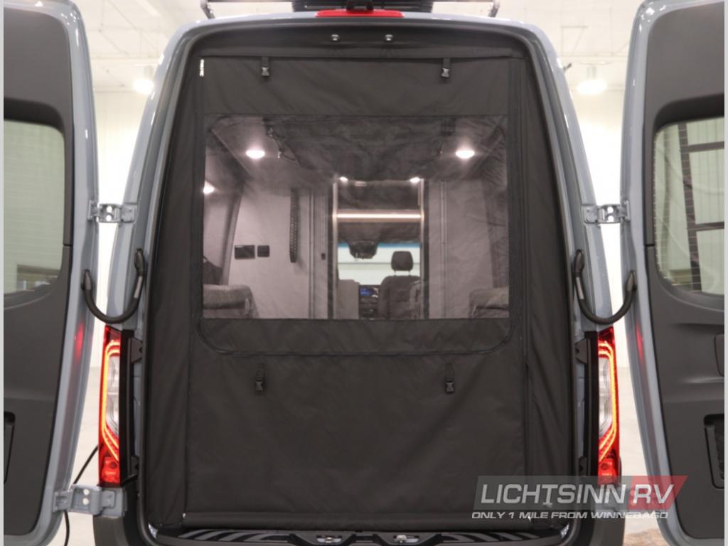 Rear view of an RV rental with open doors, featuring a black mesh screen for ventilation and privacy. Shows the camper's interior.
