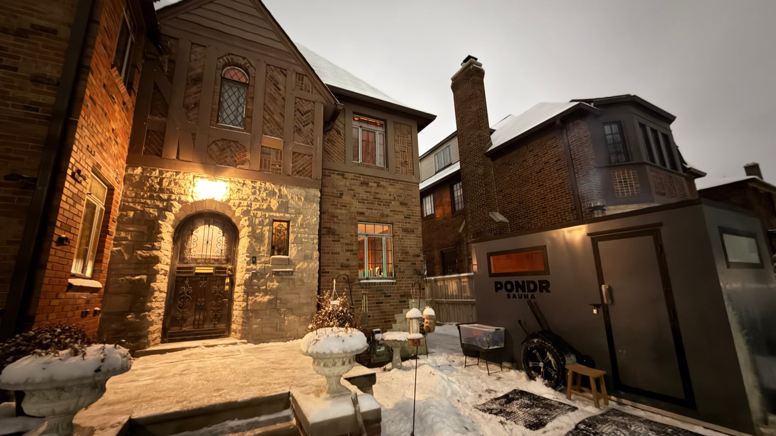 Snowy landscape with a historic home & modern Pondr Sauna. Offers a unique, portable experience, like an RV rental.