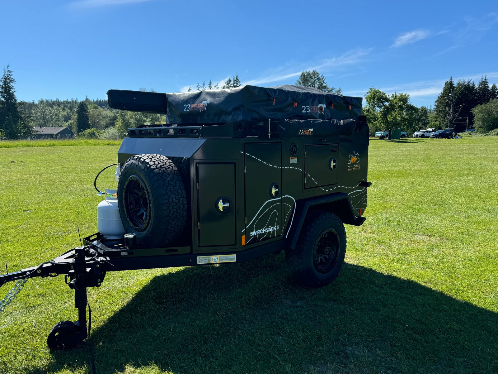 This rugged Off Grid Switchbacks RV rental, featuring a 23ZERO rooftop tent, is ready for off-road adventures on green grass.