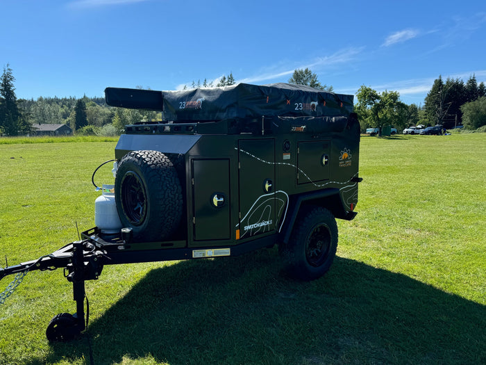 This rugged Off Grid Switchbacks RV rental, featuring a 23ZERO rooftop tent, is ready for off-road adventures on green grass.
