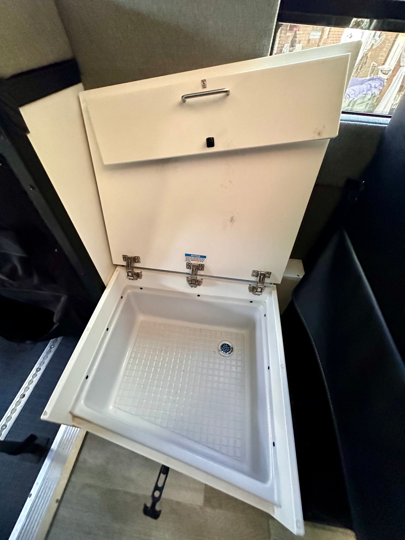 An open ice chest with a drain, built into the interior of an RV rental.
