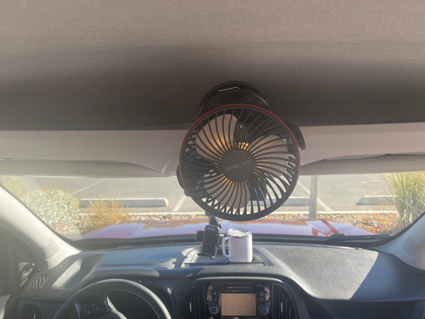 Portable fan mounted on rv rental ceiling, dashboard with phone holder & mug. Enhancing your journey comfort.