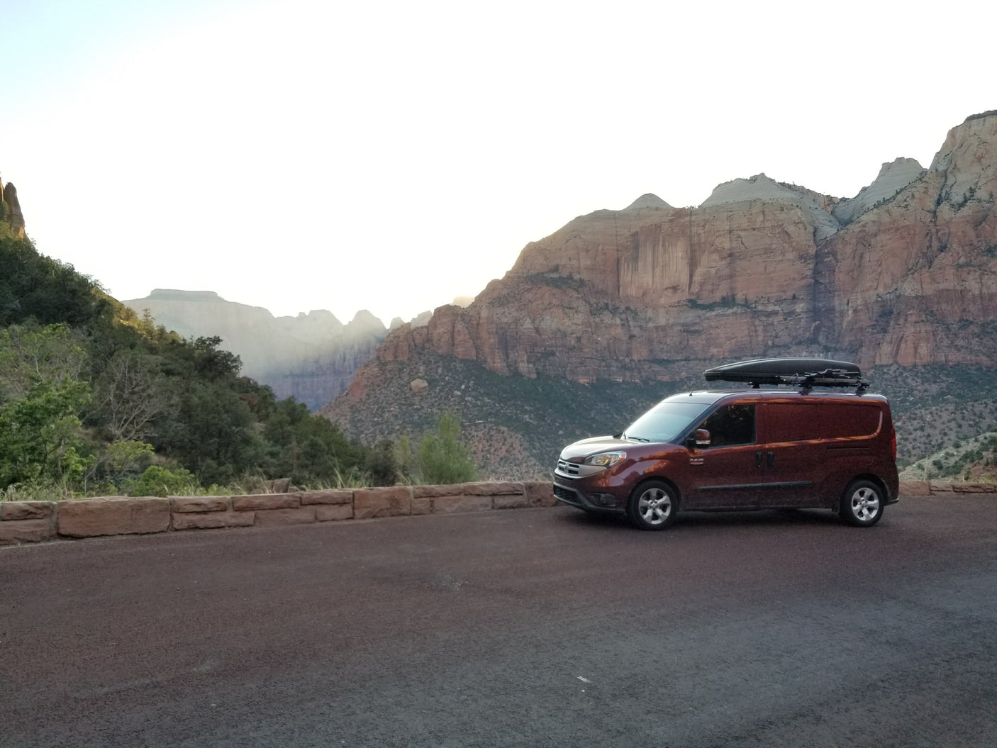 This rv rental camper van with a roof box enjoys a stunning mountain view at a national park, perfect for a scenic trip.