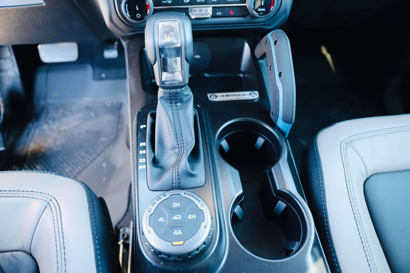 RV rental's rugged interior: Automatic shifter with Bronco emblem, G.O.A.T. modes 4x4 dial, and cup holders ready for adventure.