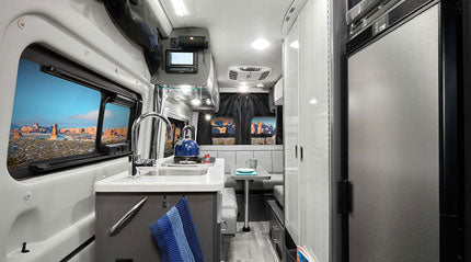 Modern RV rental interior with compact kitchen, dining area, and large window showcasing a desert view. Ready for adventure.