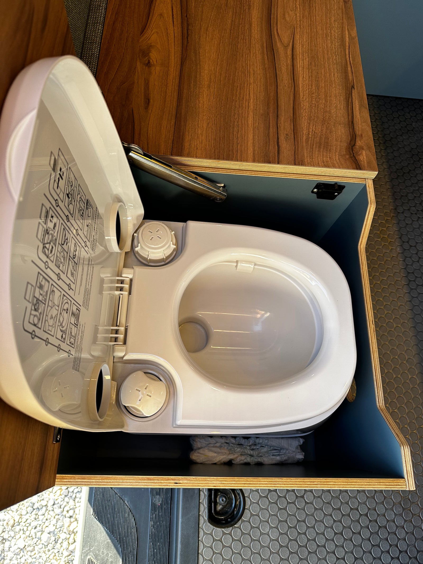 Compact RV rental toilet setup with open lid, showing its design and integrated storage.