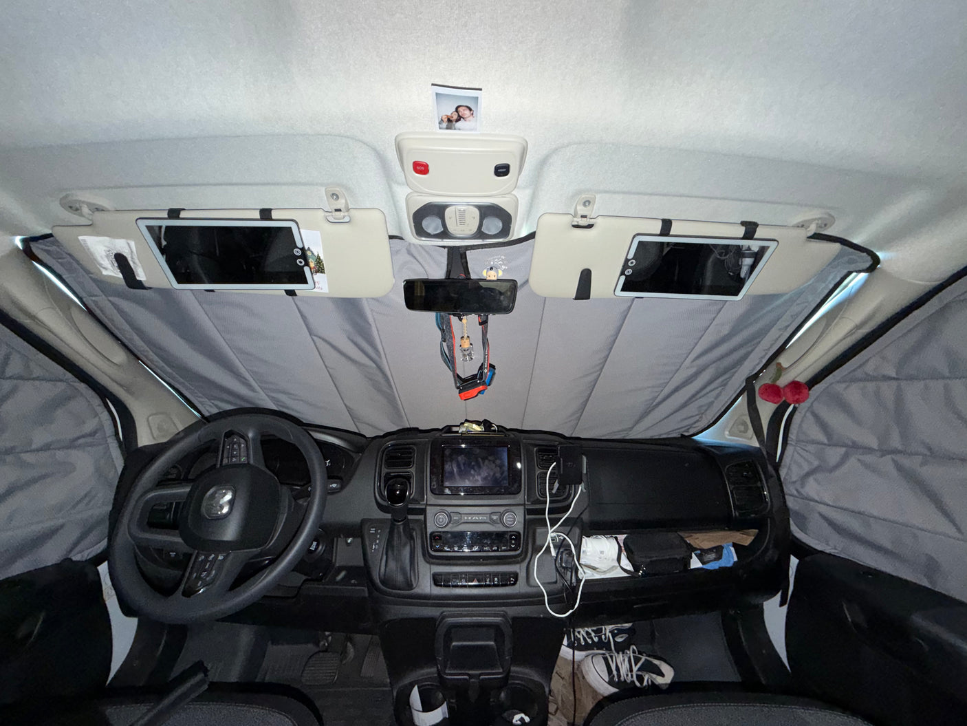 Front cabin of an RV rental, showcasing the dashboard, steering wheel, and full window sunshades for privacy and comfort.