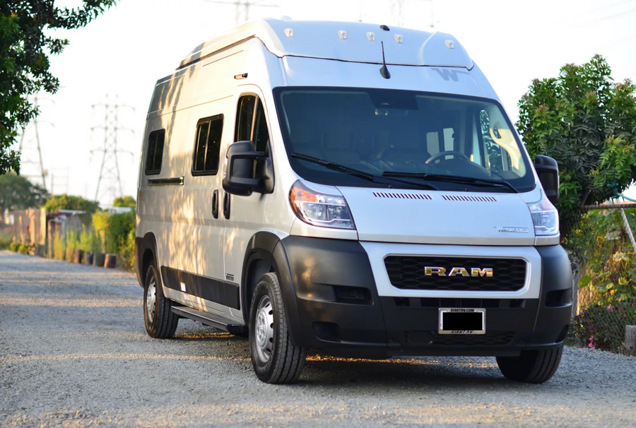 Front view of a silver Winnebago camper van on a RAM ProMaster chassis, ideal for rv rental, parked on gravel.