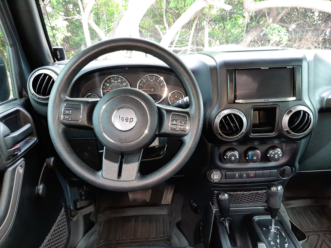 Interior of a Jeep Wrangler: dashboard, steering wheel, auto shifter. Ready for rugged trips, like those paired with an rv rental.