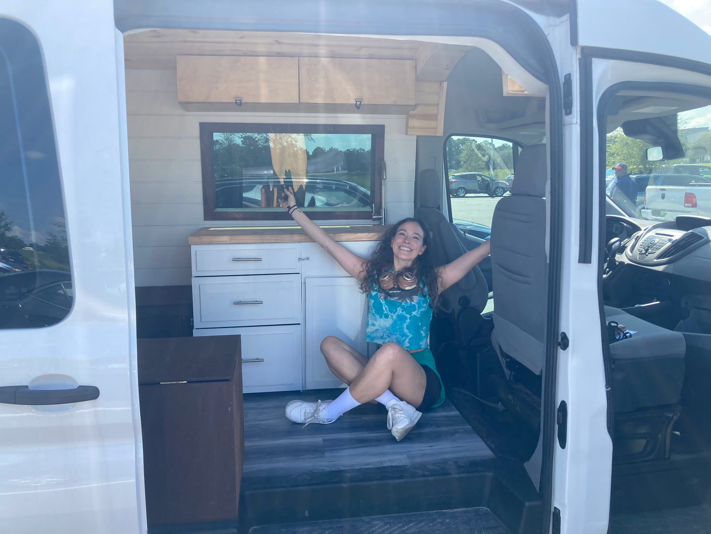 Joyful woman in a spacious, converted van with wood accents. Consider this RV rental for your next van life adventure!