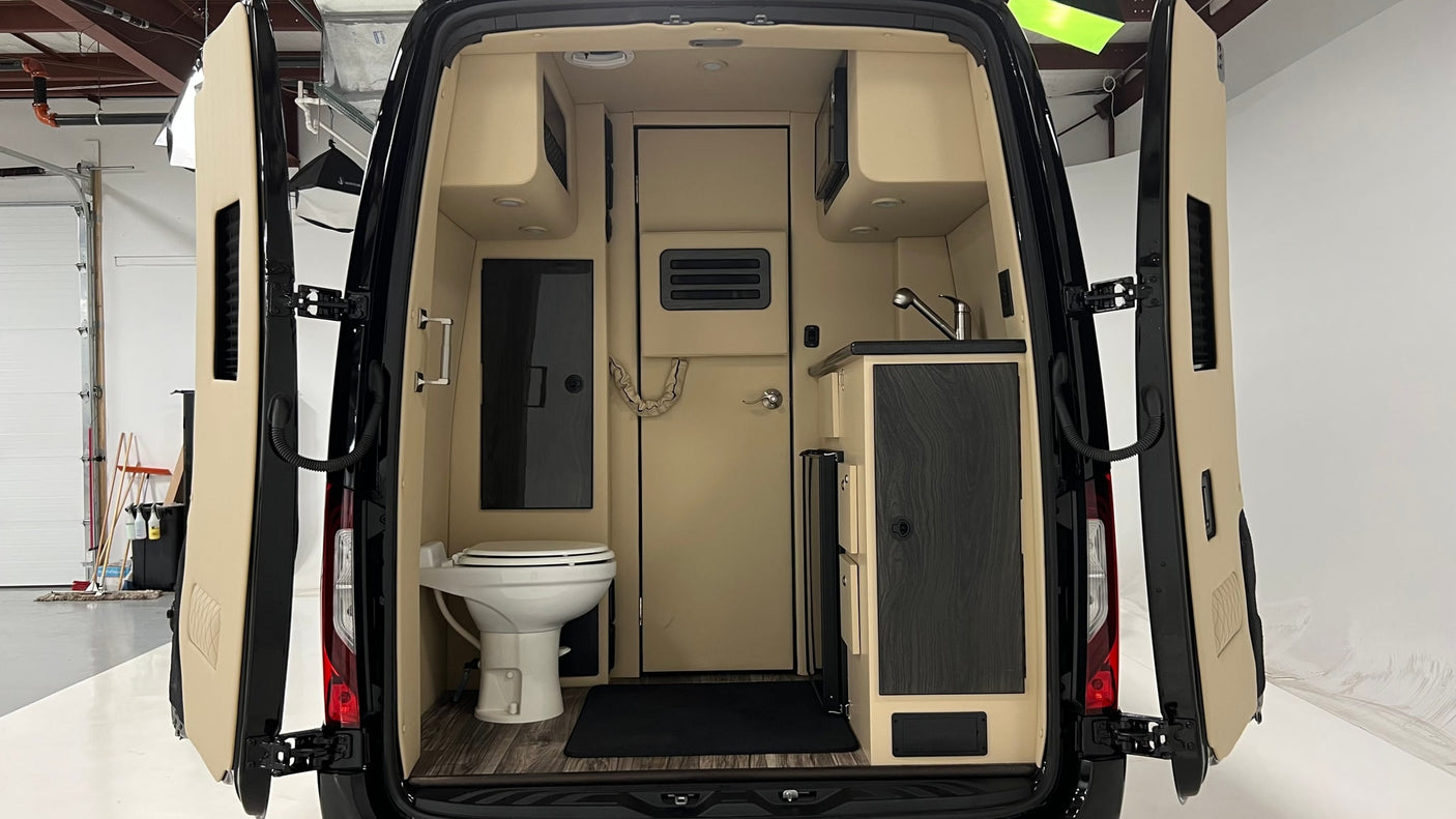 Inside this RV rental's camper van, find a compact kitchen with a sink & microwave, plus a small bathroom with a toilet.