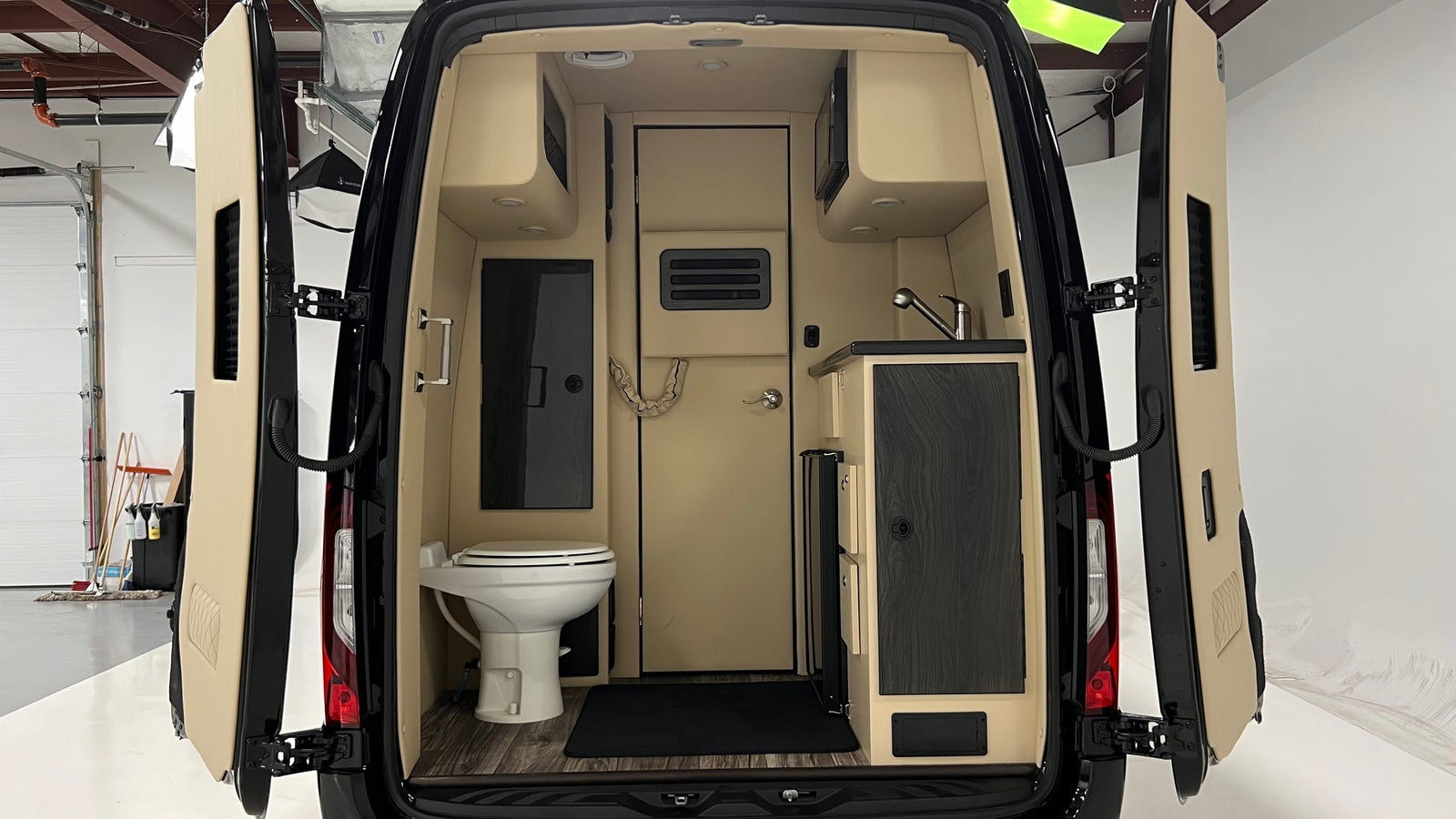 Inside this RV rental's camper van, find a compact kitchen with a sink & microwave, plus a small bathroom with a toilet.