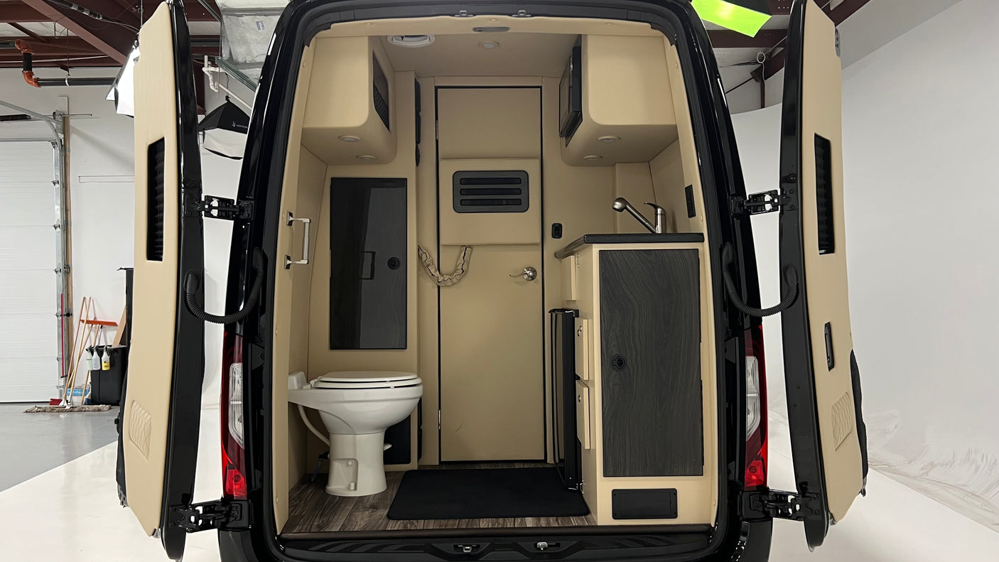 Inside this RV rental's camper van, find a compact kitchen with a sink & microwave, plus a small bathroom with a toilet.