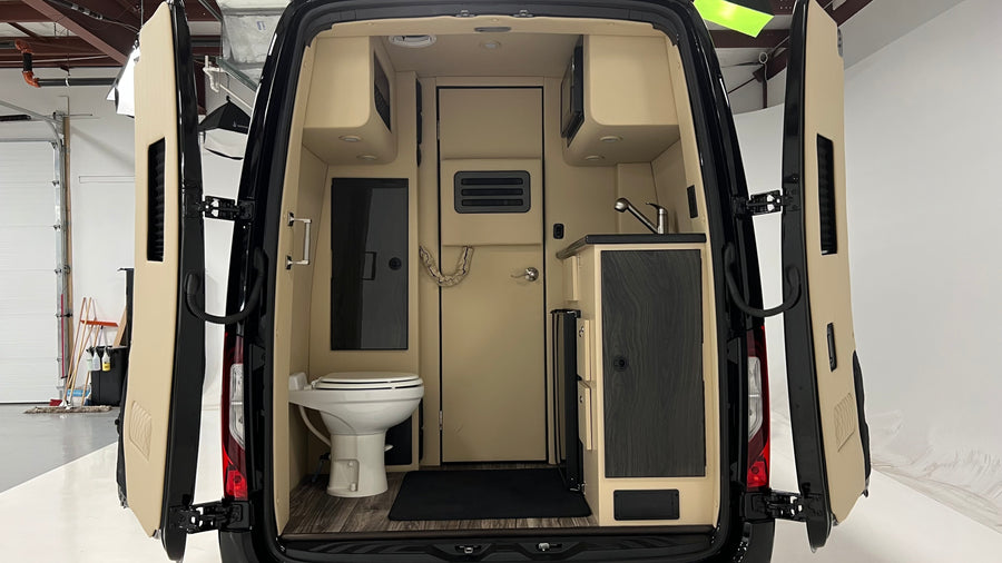 Inside this RV rental's camper van, find a compact kitchen with a sink & microwave, plus a small bathroom with a toilet.