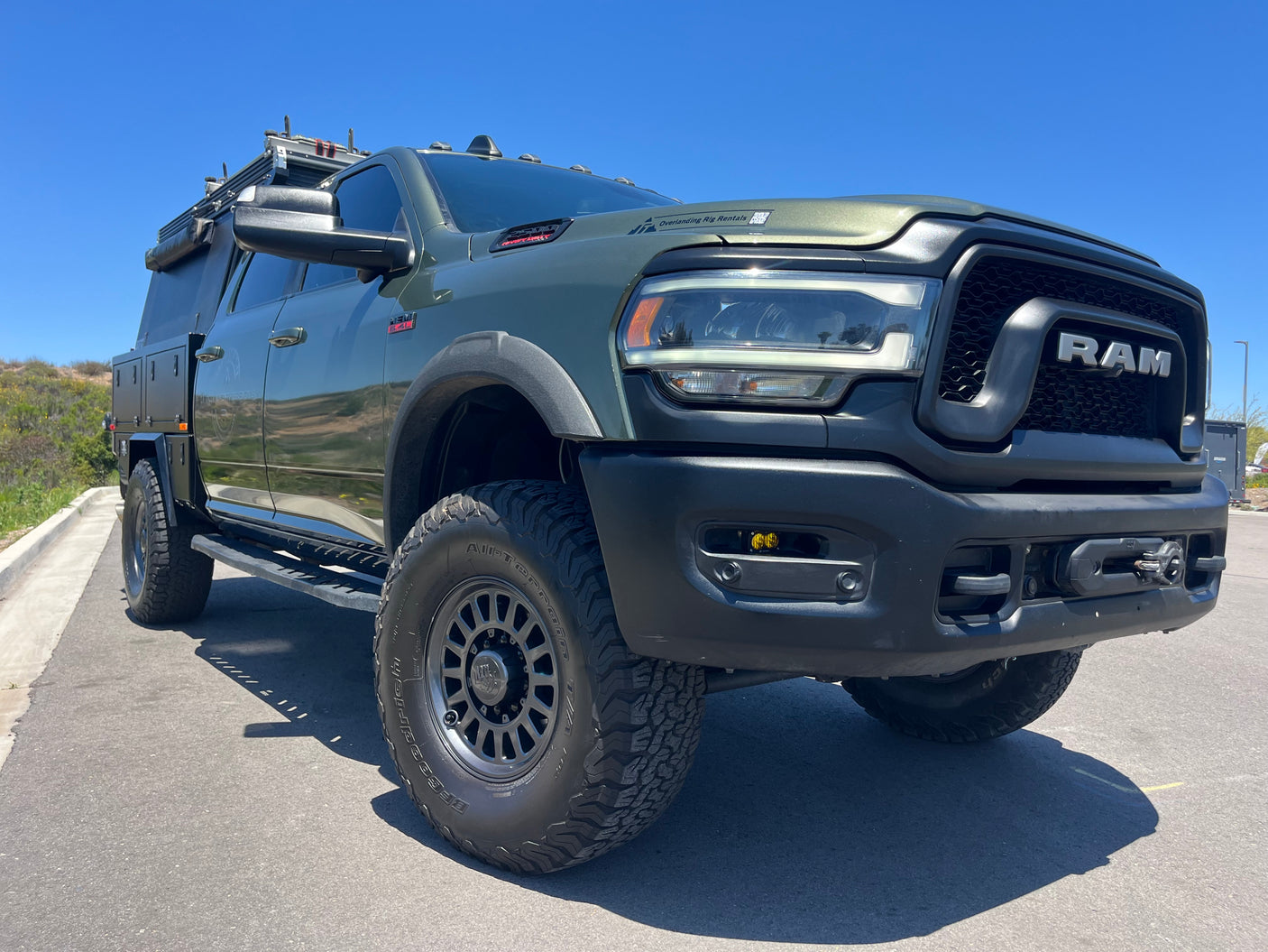 Front view of a rugged green Ram overlanding truck, equipped with a custom bed & winch. Ideal for an RV rental adventure.