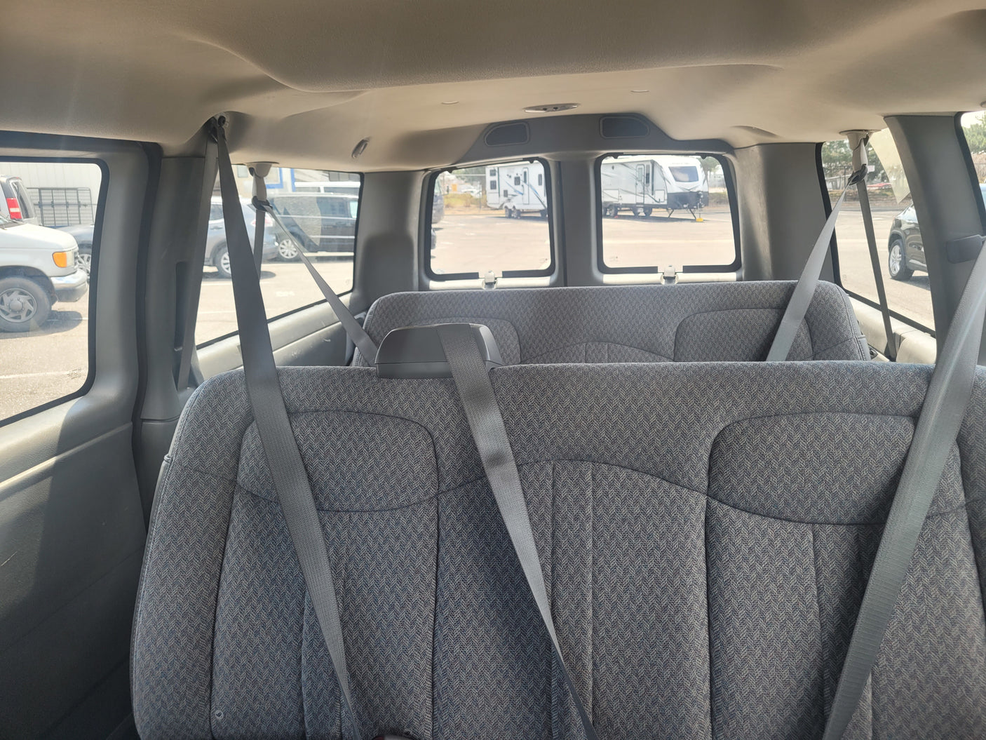 Passenger van interior, showing rear seats and view of RVs outside, suggesting an RV rental pick-up.