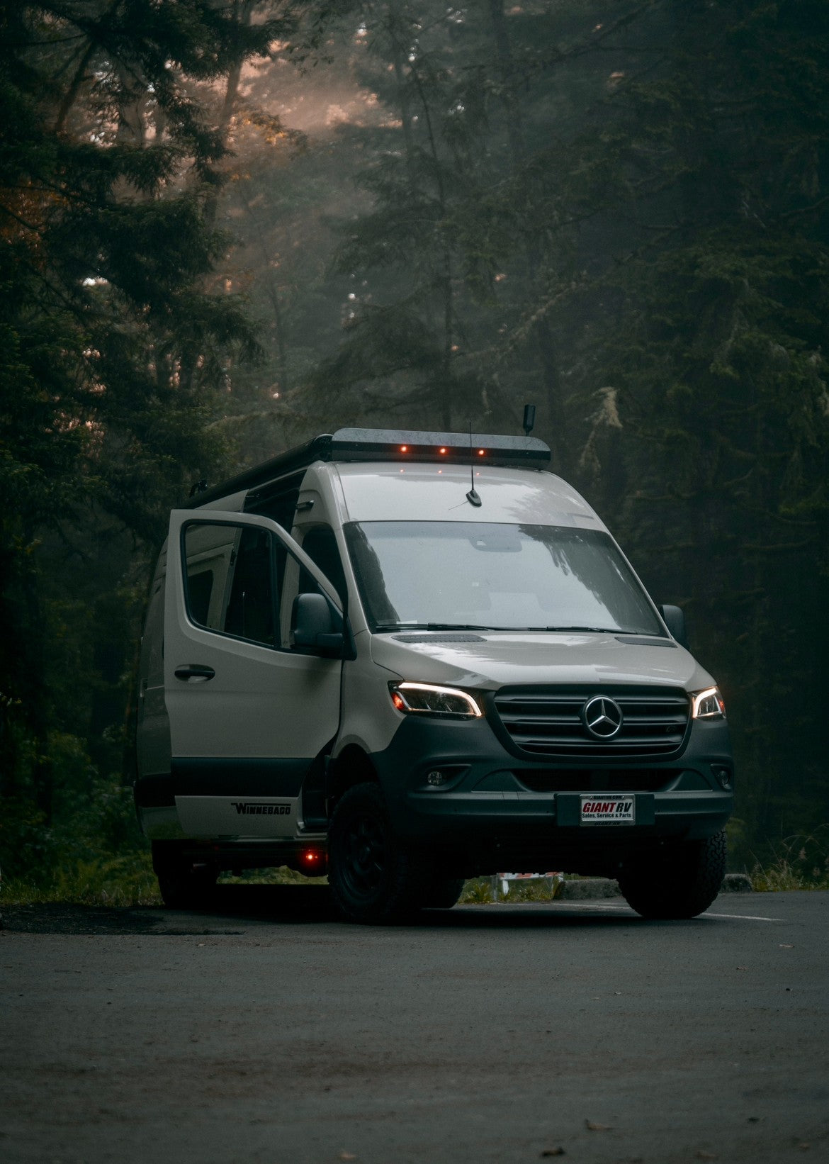 Misty forest RV rental: a white Mercedes camper van, door open, perfect for an off-grid nature adventure.