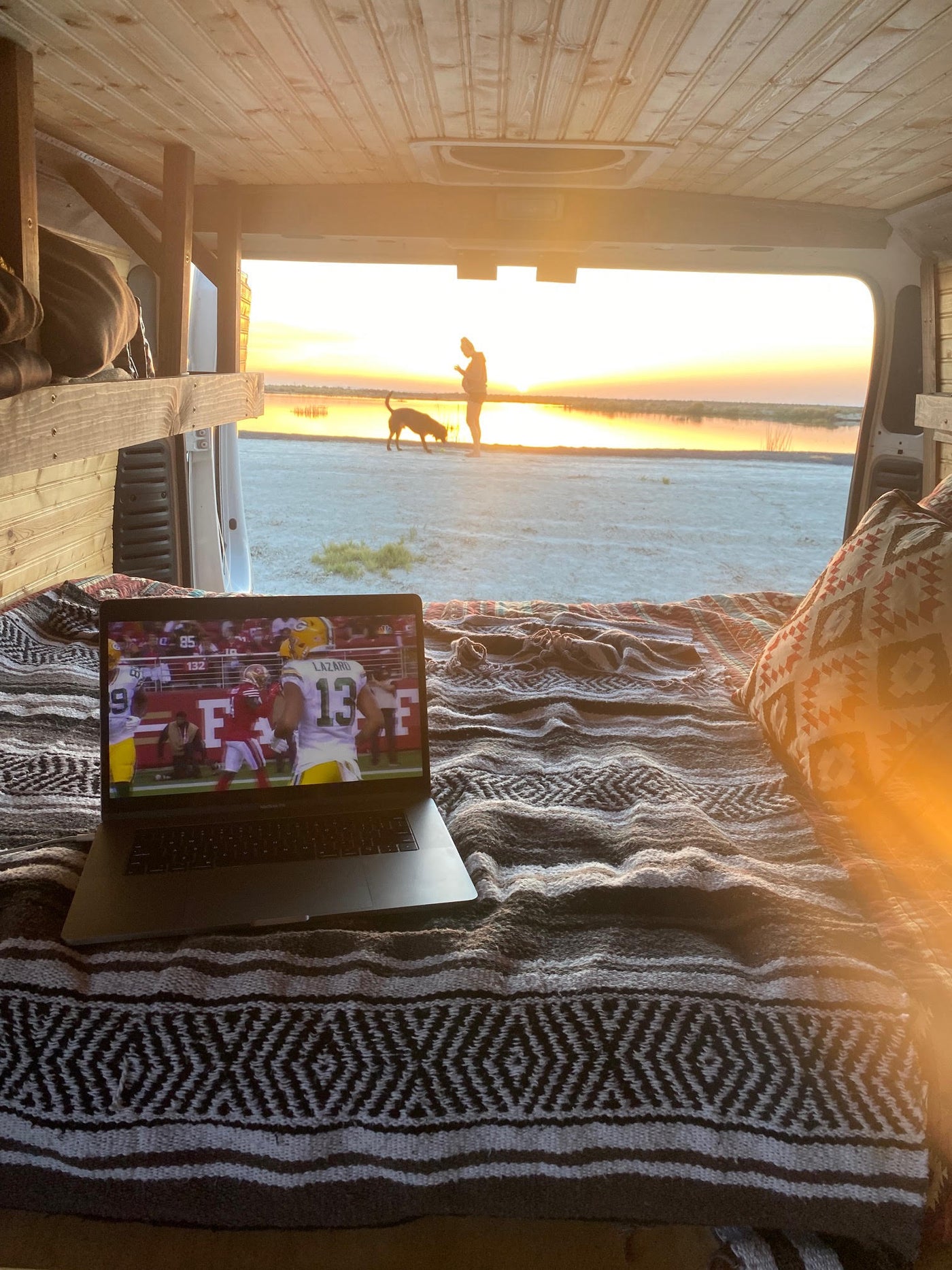 with a dog watching the snowy lake & mountains outside. Ideal for van life travel.|Rear view of an rv rental camper van in a vast field at dusk. Interior shows a person — photo 11