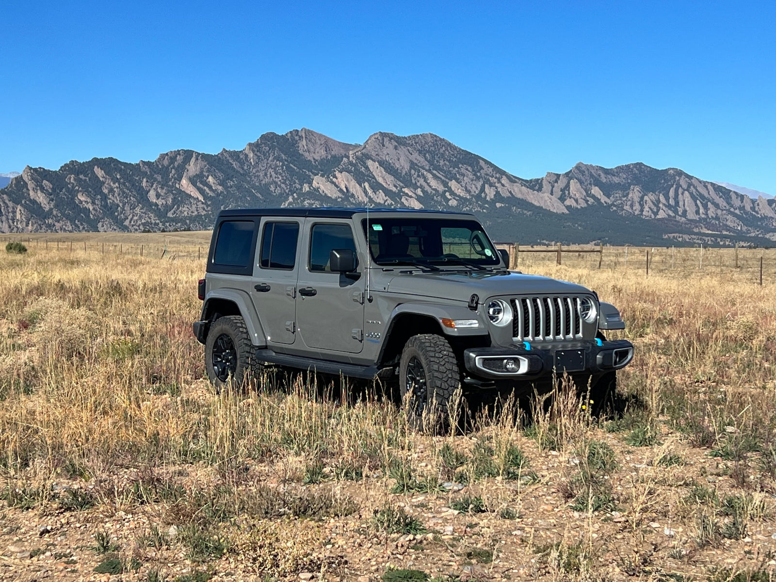Grey Jeep Wrangler 4xe in a scenic mountain field, ideal for your next RV rental road trip.