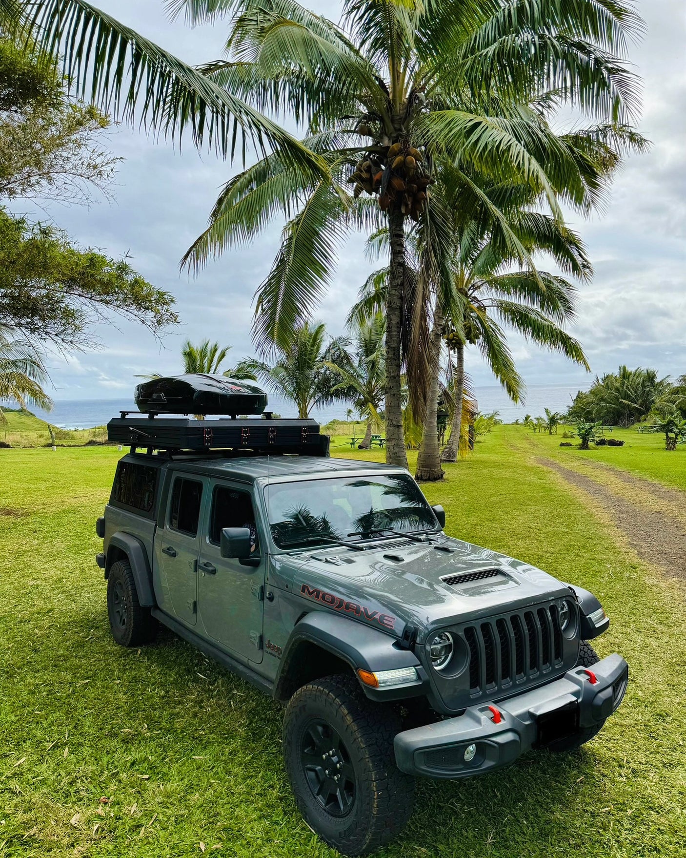 Ready for adventure: Gray Jeep Gladiator Mojave with rooftop tent, a perfect rv rental for tropical camping by the ocean.