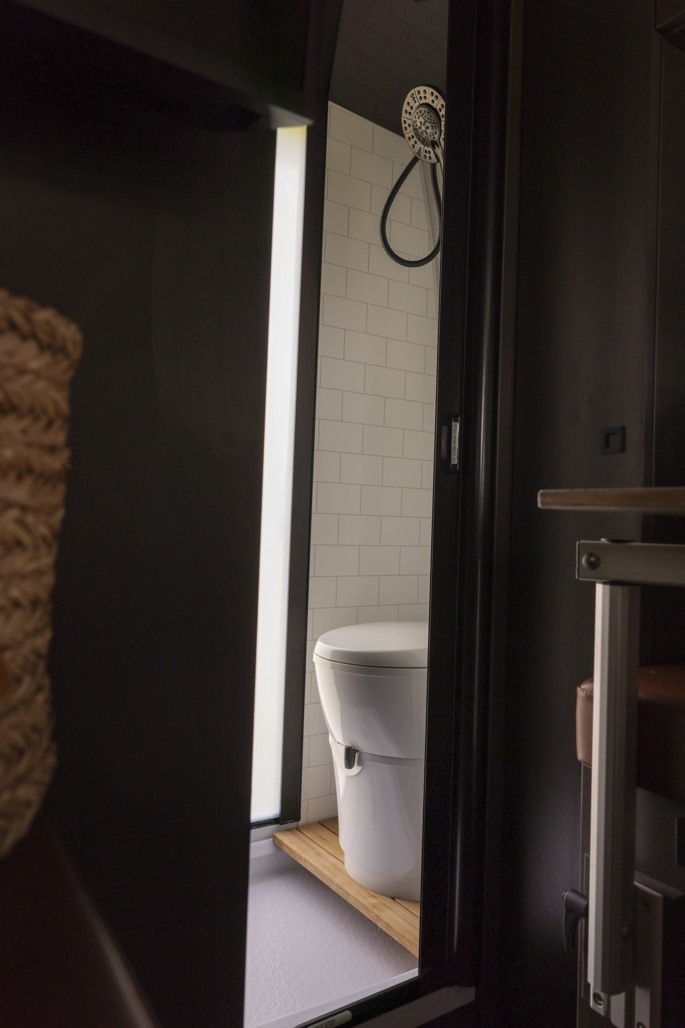 Step into this modern RV rental's compact wet bath, featuring a sleek toilet, shower, and subway tile walls.