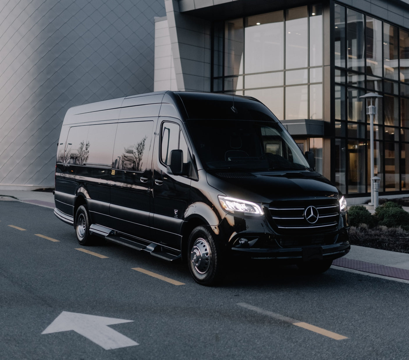 Black Mercedes-Benz Sprinter luxury van, perfect for RV rental or executive transport, parked on asphalt near a modern building.