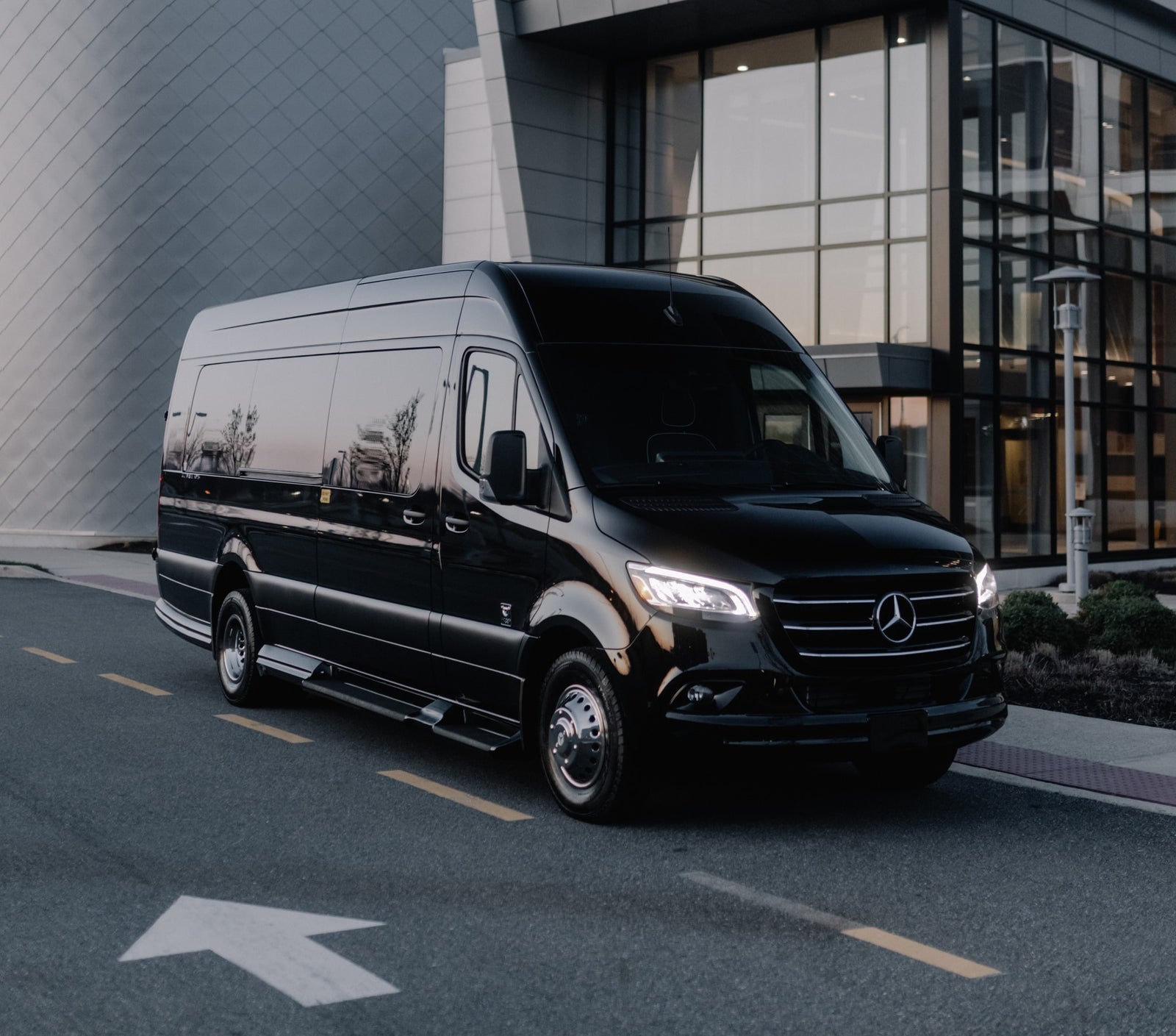 Black Mercedes-Benz Sprinter luxury van, perfect for RV rental or executive transport, parked on asphalt near a modern building.