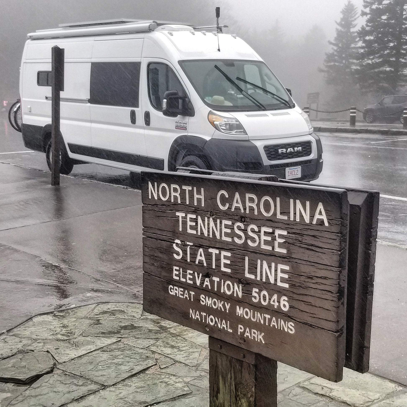 An rv rental, a white camper van, parked at the North Carolina/Tennessee state line in Great Smoky Mountains NP on a foggy day.
