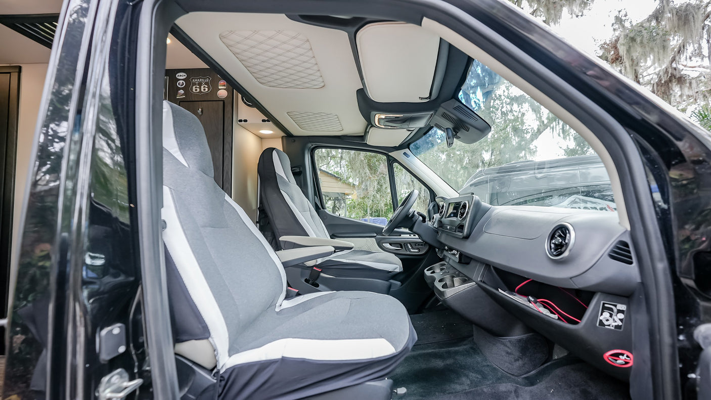 RV rental interior: Clean front cabin with grey seats, dashboard, and quilted ceiling.
