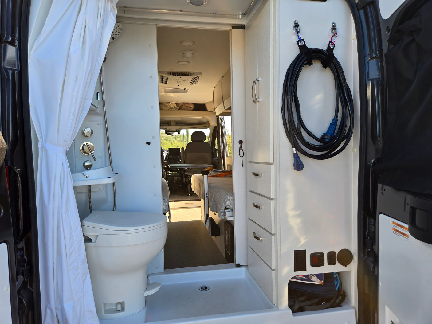 Inside a modern RV rental, featuring a shower, toilet, storage cabinets, and electrical hookups. Ready for adventure!